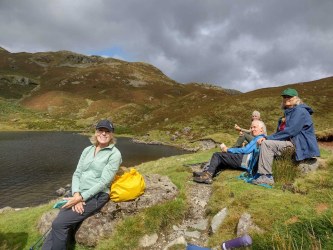 Hikers taking a break beside a mountain tarn in the Lake District fells