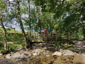 Group of hikers on a wooden footbridge over a beck in the Lake District